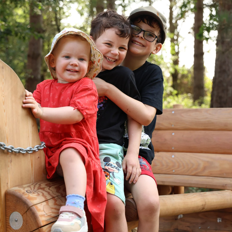 Three children laughing together on the adventure playground at Wellington Country Park
